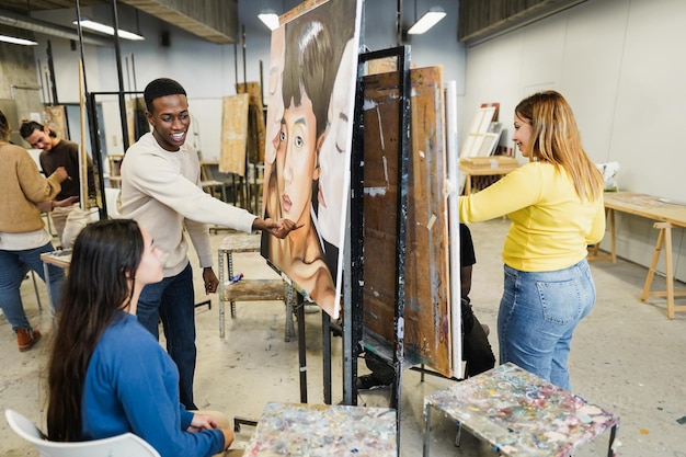 Gemischtrassige Studenten malen im Kunstraum an der Universität - Konzentrieren Sie sich auf das Gesicht eines afrikanischen Mannes