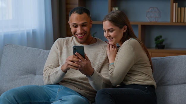 Gemischtrassiges Paar afroamerikanischer Mann und hispanische Frau gewinnen Spiel auf dem Handy und lesen gute Nachrichten