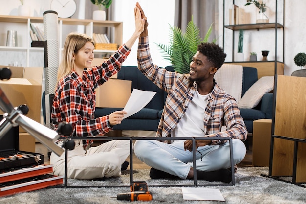 Gemischtrassiges Paar macht High Five in neuer Wohnung