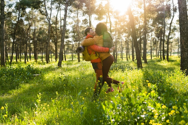 Gemischtrassiges Paar Wanderer im Wald umarmt sich bei Sonnenuntergang bei Sonnenuntergang Konzept von Backpacker-Reisenden
