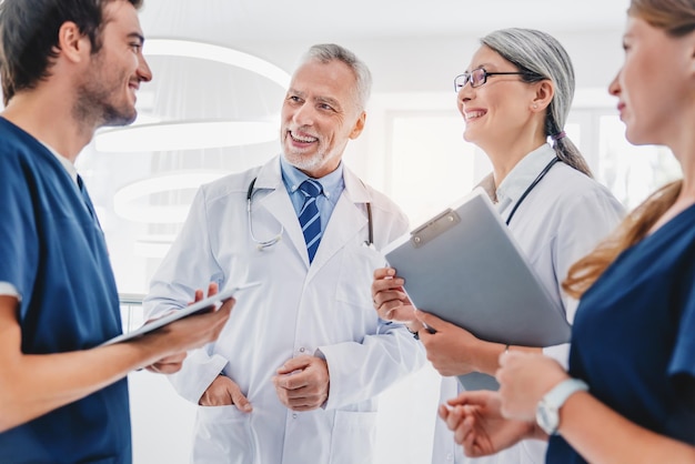 Gemischtrassiges Team von Ärzten, die über Patienten sprechen, die im Foyer der Klinik stehen