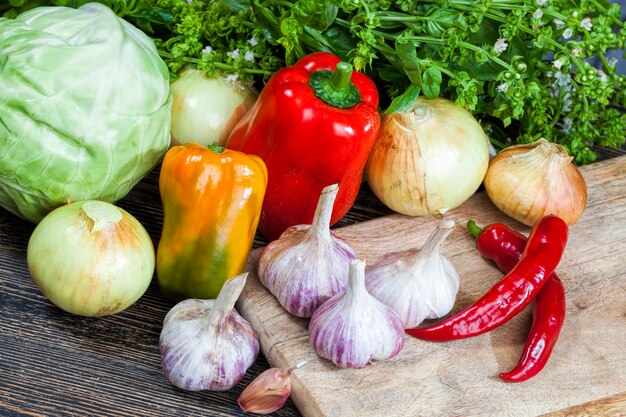 Gemüse auf dem Tisch beim Kochen, Knoblauch, Pfefferzwiebeln, Gemüse und Gewürze auf dem Schneidebrett