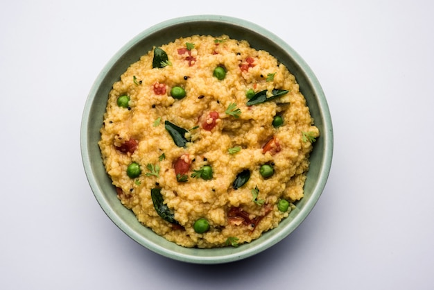 Gemüse Dalia oder Daliya Khichadi oder Broken Wheat Khichdi mit Tomaten, grünen Erbsen und Chili, serviert in einer Schüssel oder einem Teller