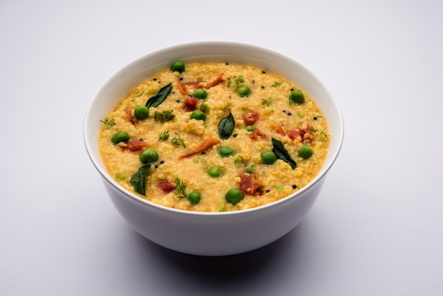 Gemüse Dalia oder Daliya Khichadi oder Broken Wheat Khichdi mit Tomaten, grünen Erbsen und Chili, serviert in einer Schüssel oder einem Teller