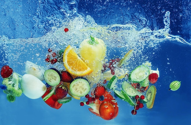 Gemüse und Früchte, die auf farbigem Hintergrund ins Wasser fallen