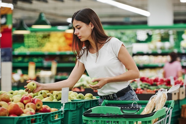 Gemüse und Früchte. Weibliche Käuferin in Freizeitkleidung auf dem Markt, der nach Produkten sucht.