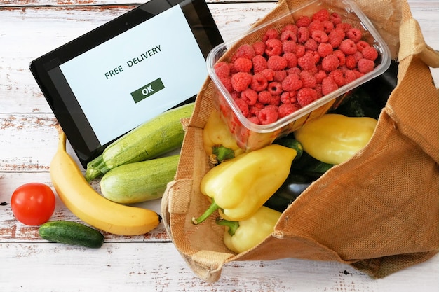 Gemüse und Obst in Baumwolltasche und Tablet-PC, Online-Marktkonzept