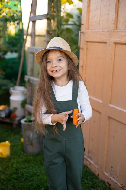 Foto gemüsegarten ein lustiges kleines mädchen bauer beißt eine karotte ein milchzahn fiel aus lifestyle platz für text