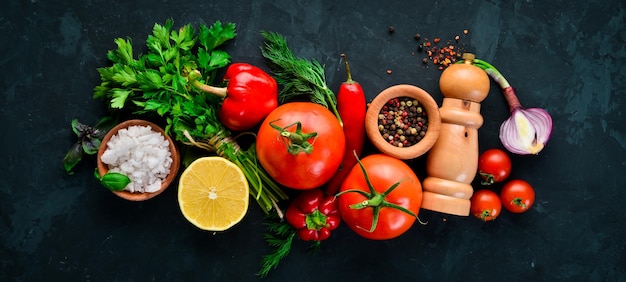 Gemüsehintergrund Frische Tomaten, Paprika, Zwiebeln und Petersilie auf dem Tisch Draufsicht auf schwarzem Hintergrund Freier Platz für Text