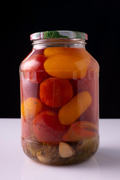 Gemüsekonserven in einem Glas auf einem weißen Tisch und schwarzem Hintergrund