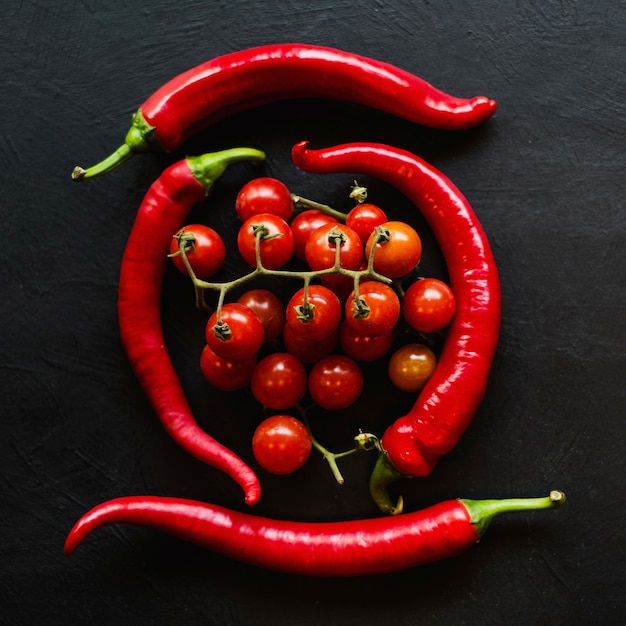 Gemüsepaprika und Tomaten auf dunkler Oberfläche. Zutaten für scharfe Soße. Zubereitung von Speisen.