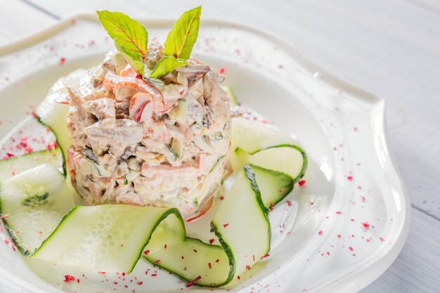 Gemüsesalat mit Fleisch, Kräutern, Gurke und Gewürzen auf weißer Platte