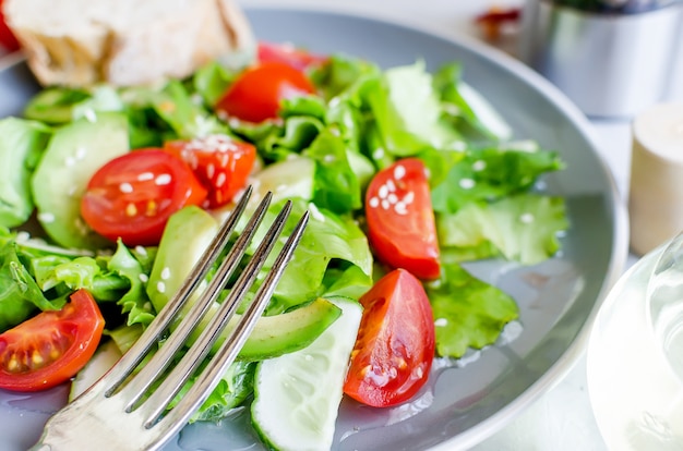 Gemüsesalat mit frischen Tomaten, Gurken, Avocado, Gemüse und Zwiebeln mit Sesam