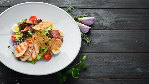 Gemüsesalat mit Hähnchenfilet und Speck Draufsicht freier Platz für Ihren Text Rustikaler Stil