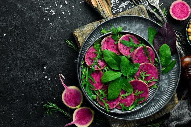 Gemüsesalat Spinat Wassermelone Rettich schwarzer Sesam und Olivenöl Veganes Essen Draufsicht auf Steinhintergrund