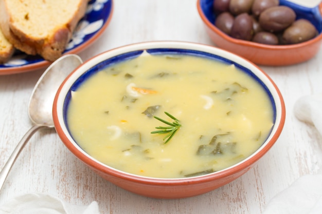 Gemüsesuppe in Schüssel und Oliven mit Maisbrot