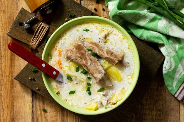 Gemüsesuppe mit Sauerrahm Kohl und Fleischrippen auf einem Küchenholztisch Ansicht von oben