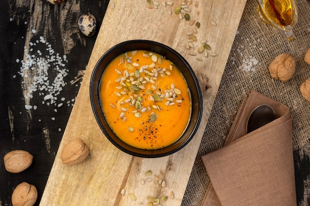 Foto gemüseteller-kürbissuppe mit samen auf einem hölzernen schneidebrett, draufsicht