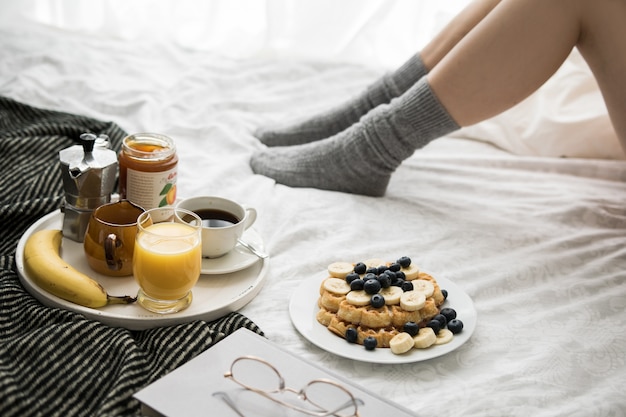 Gemütliche Frühstücksszene im Bett an einem Wochenende mit Kaffee und Waffeln