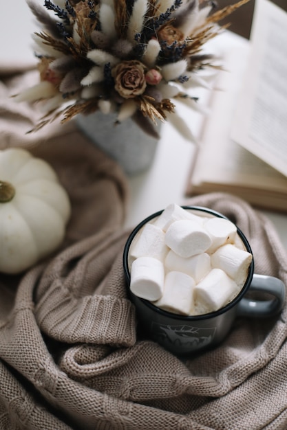 Gemütliche Heimherbstdekoration mit einer Tasse Kaffeebuch Kürbisblüten und Plaid