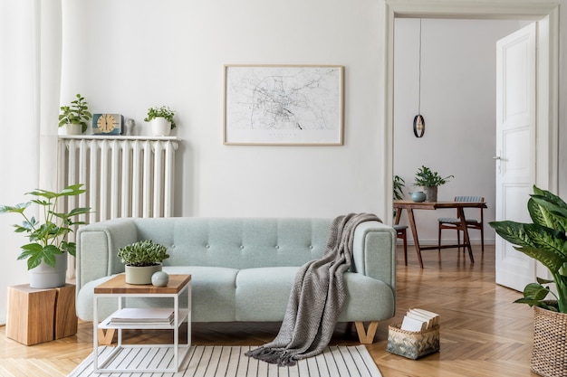 Foto gemütliche und kreative komposition aus stilvoller wohnzimmereinrichtung mit rahmen, grünem sofa, holzmöbeln, pflanzen und accessoires. weiße wände, parkettboden.