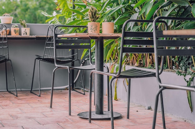 Gemütliche Veranda Balkon Terrasse Open Air Café im tropischen Stil Metallstuhl Tischmöbel Grüne Naturblätter Sommertag Modernes Dekor Interieur warme Atmosphäre Entspannen Sie sich im Freien