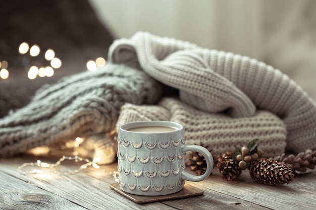 Gemütliche Winterkomposition mit Tasse und Dekordetails auf unscharfem Hintergrund.