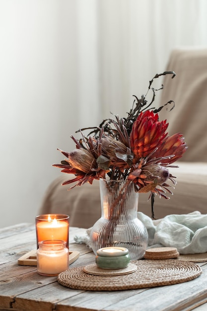 Gemütliche Wohnkomposition mit Kerzen und Protea-Bouquet