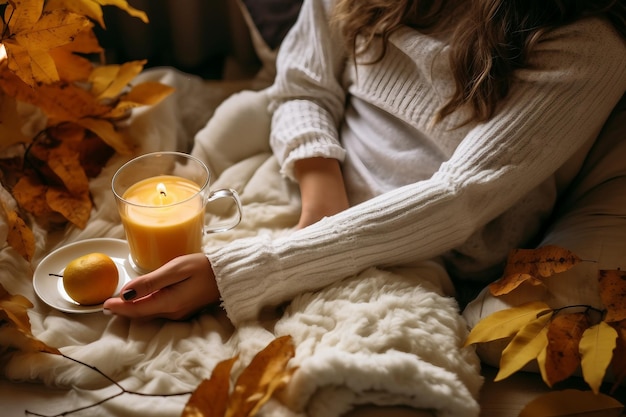 Gemütlicher Herbst zu Hause, eine Frau mit Tee und einem Buch, die sich ausruht. Eine gemütliche Lebensart. Körperteile in der Komposition