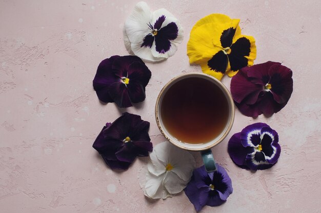 Gemütlicher Morgen mit Tasse Tee und bunter Viola-Blumen-Draufsicht