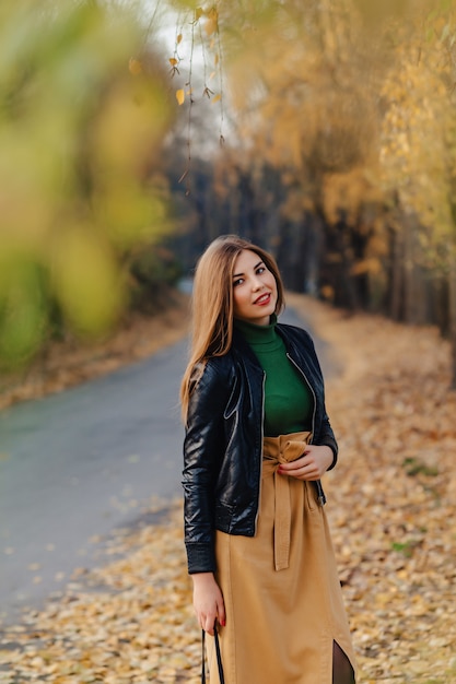 Gemütlicher stilvoller Weg des jungen Mädchens am Herbstpark