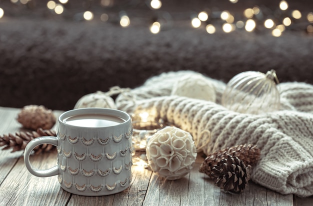 Gemütlicher weihnachtshintergrund mit einer schönen tasse und dekordetails auf einem unscharfen hintergrund mit bokeh.