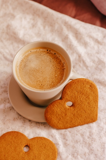 Gemütlicher Winter- oder Herbstmorgen zu Hause. Heißer Kaffee, Kekse warme Decke und Girlande, schwedisches Hygge-Konzept.