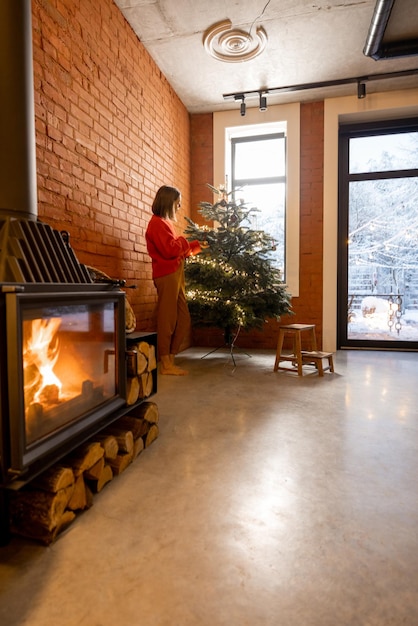 Gemütlicher Wohnzimmerinnenraum mit Frau, die Weihnachtsbaum verziert