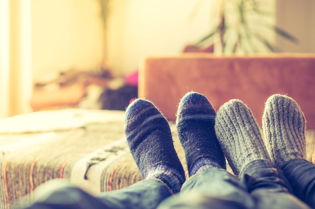 Gemütliches Entspannen im Winter zu Hause Paar mit Wollsocken liegt auf der Couch