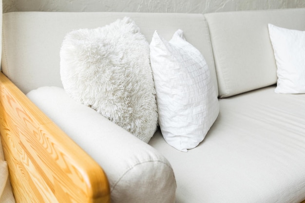 Gemütliches hellgraues Sofa mit weißen Kissen und Armlehnen aus Holz