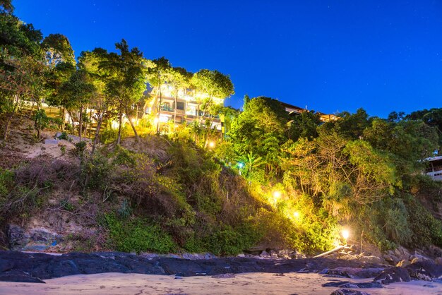 Gemütliches, im Sommer beleuchtetes Hotel auf einer Felsklippe in der Nähe des Meeressandstrandes bei Nacht