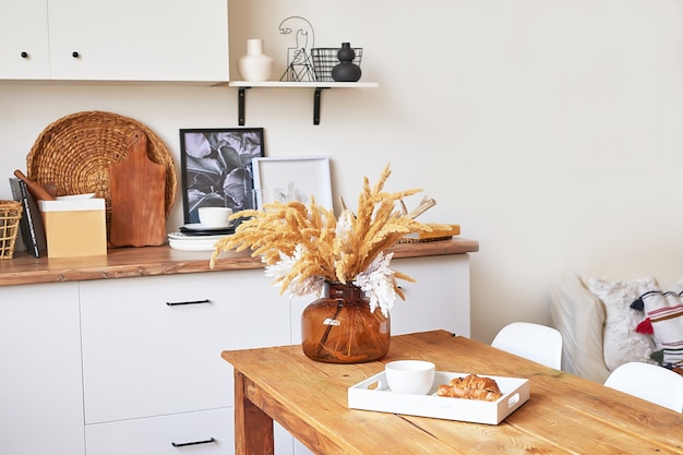 Foto gemütliches interieur der hellen küche im loft-stil. weißes küchenset. küchenzubehör. regale und geschirr. guten morgen. stilvolles luxus-interieur im studio-apartment-design mit holzmöbeln.