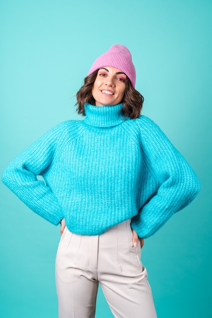 Gemütliches Porträt einer jungen Frau in einem blauen Strickpullover und einer rosa Mütze mit hellem Make-up