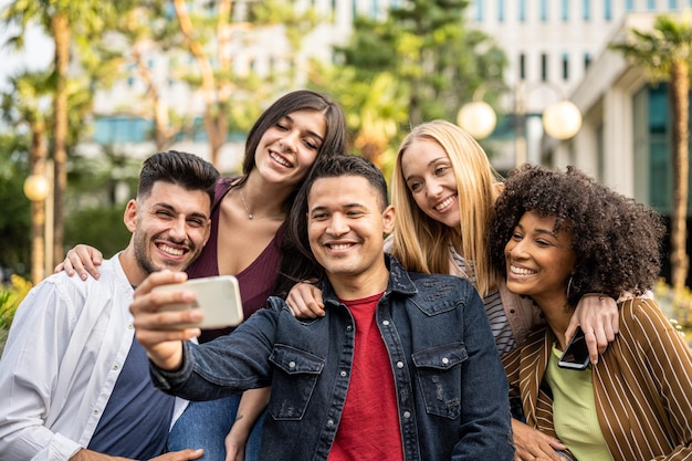 Gen z-Leute, die Selfie mit Smartphone machen, fünf Personen, die Spaß im Freien haben und Freundschaft verbinden