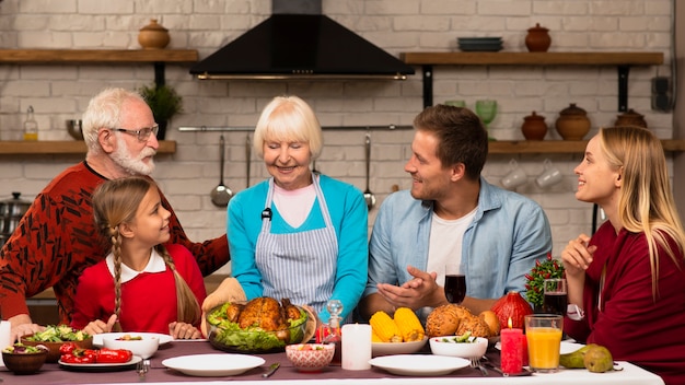 Foto generaciones familiares sentados en la mesa de acción de gracias