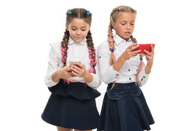 Generation der mobilen Kommunikation Kleine Schüler mit mobilen Geräten, isoliert auf weiss Kleine Schulkinder mit E-Lesson auf Mobiltelefonen Mlearning oder mobiles Lernen