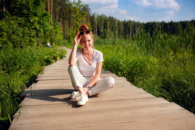 Gengibre encantadora mulher jovem linda verde floresta. Menina caucasiana, relaxando e curtindo a vida na natureza ao ar livre.