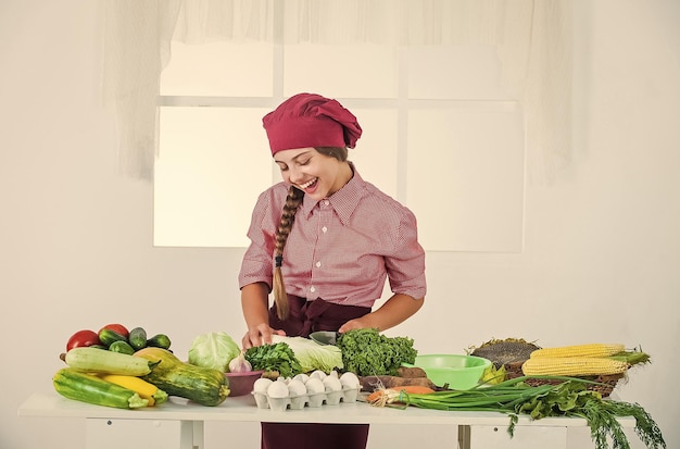 Genießen Sie den Prozess Gesunde Ernährung und Lifestyle-Konzept Grünes vegetarisches Lebensmittelmädchen mit einer Vielzahl von Vitaminen Diät und Gesundheit Kind, das Spaß mit Lebensmittelgemüse in der Küche hat Kind und Gemüse