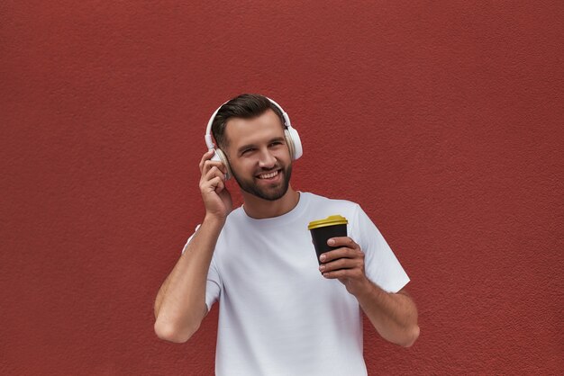 Genießen Sie dieses Tagesporträt eines glücklichen, gutaussehenden Mannes mit Kopfhörern, der die Musik hört und