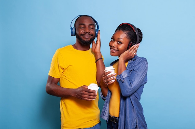 Gente alegre escuchando la lista de reproducción de música en los auriculares, disfrutando de la canción en los auriculares. Hombre y mujer en relación divirtiéndose con audio en radio en línea, usando accesorios para auriculares.