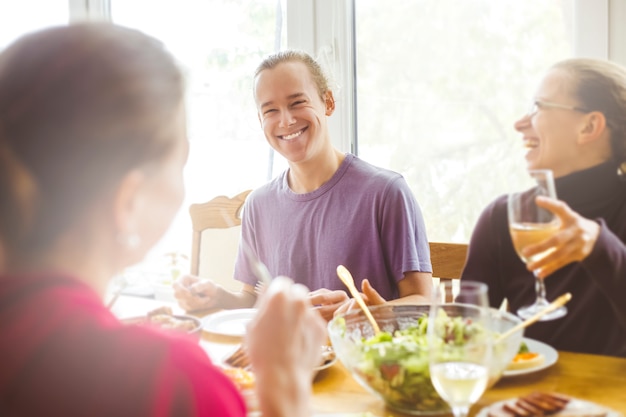 Gente alegre está hablando en la mesa de la cocina.