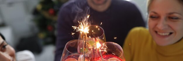 Gente alegre y feliz celebra cócteles alcohólicos con bengalas de cerca