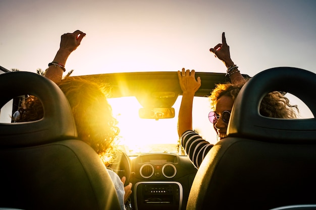 Gente alegre y feliz conduciendo y viajando para las vacaciones de verano y actividades de ocio al aire libre con un automóvil convertible riendo y bailando como locos