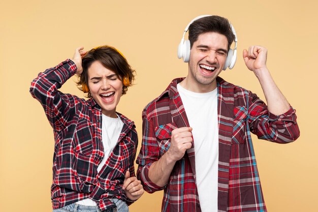 Foto gente alegre y feliz escuchando música con auriculares elegantes bailando activamente con los ojos cerrados